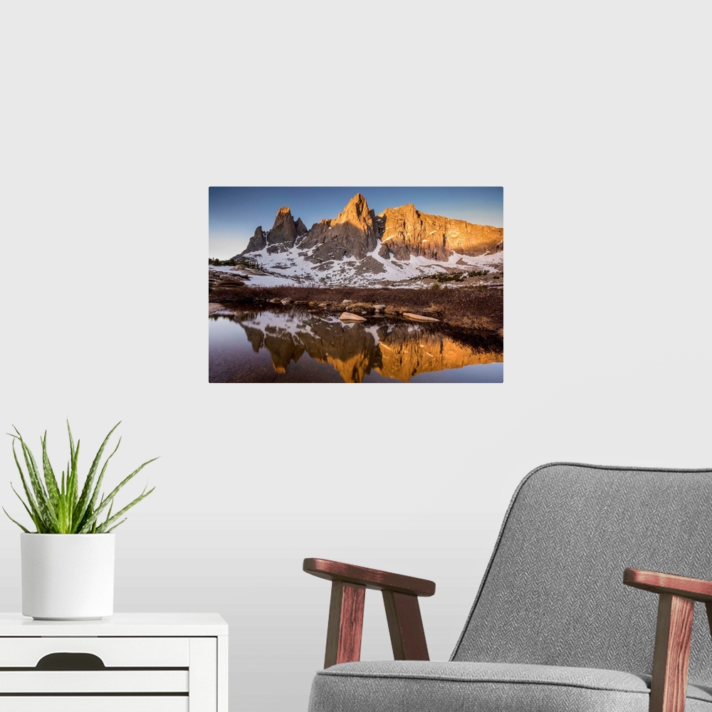 A modern room featuring Landscape photograph of a rocky mountain range covered in snow reflecting onto still water.