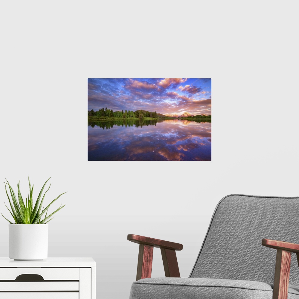A modern room featuring Vibrant clouds over a lake at dawn.