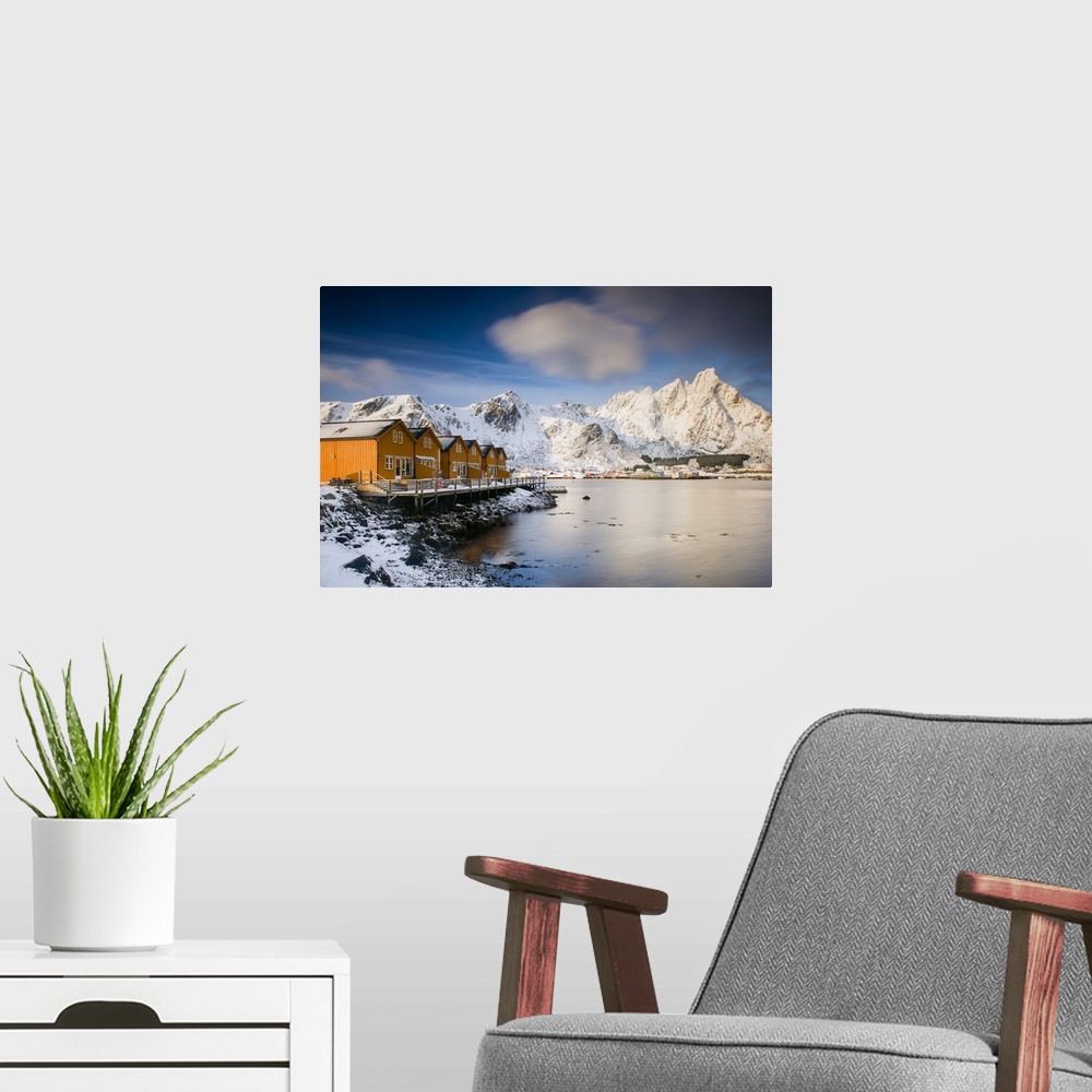 A modern room featuring A photograph of a Norwegian yellow cabin village seen with a mountain covered in snow in the back...