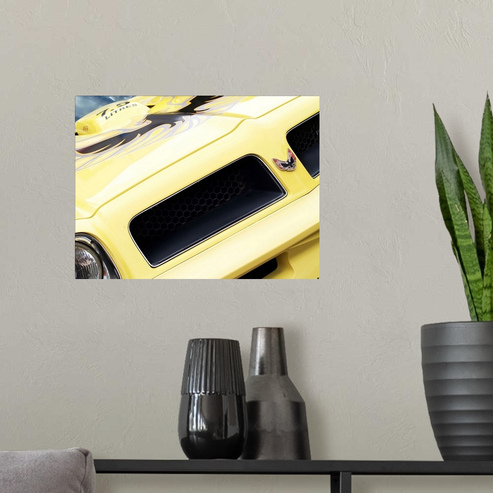 A modern room featuring Angled photograph of the front of a yellow 1976 Pontiac Trans Am.