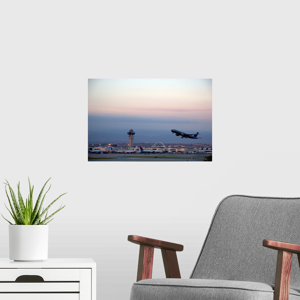 A modern room featuring Boeing 767 airplane taking off at LAX airport, Los Angeles, California at dusk.