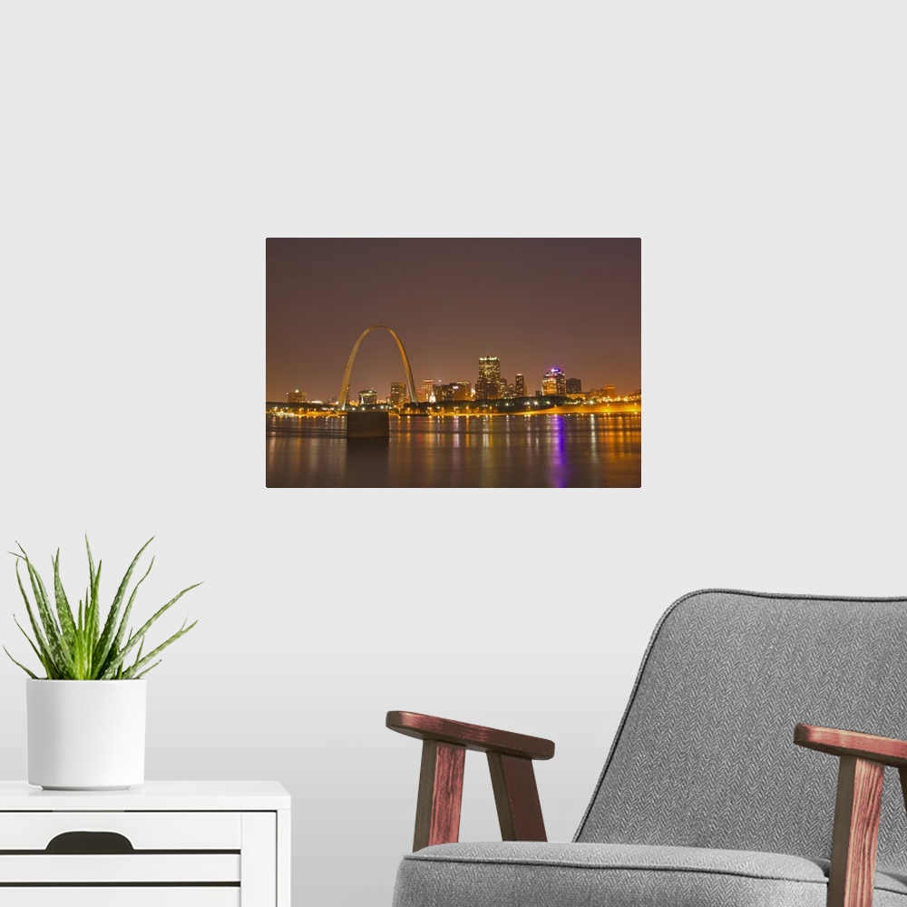 A modern room featuring The Gateway Arch and St Louis skyline reflect into the Mississippi River at dusk in St Louis, Mis...