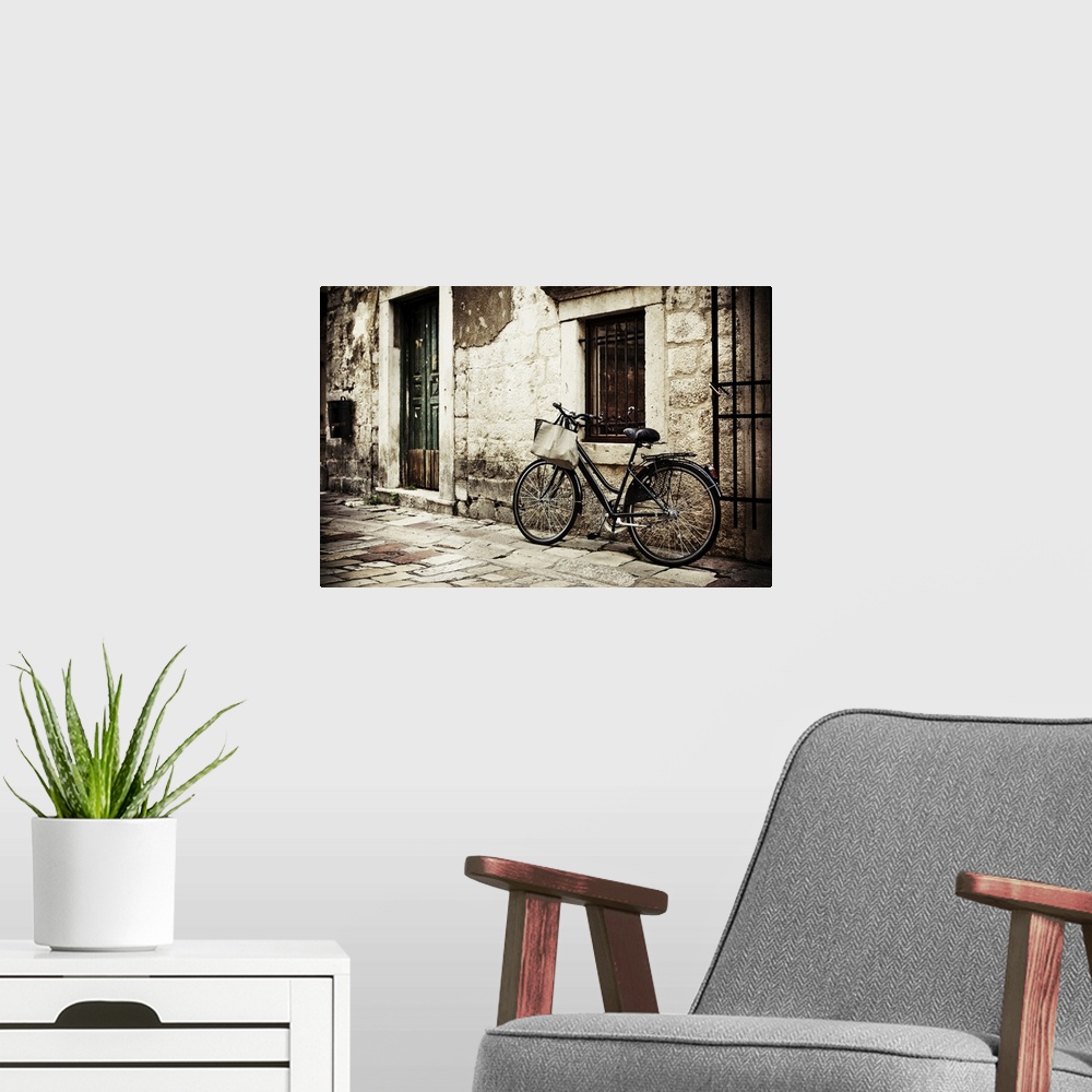 A modern room featuring Bicycle with a shopping bag on handle bar, left beside old stone wall.