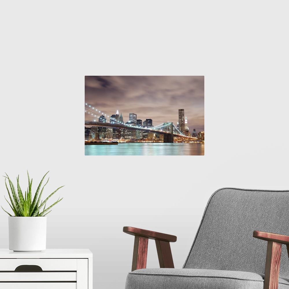 A modern room featuring Panoramic view of Manhattan with Brooklyn Bridge at night and skyscrapers illuminated over Hudson...