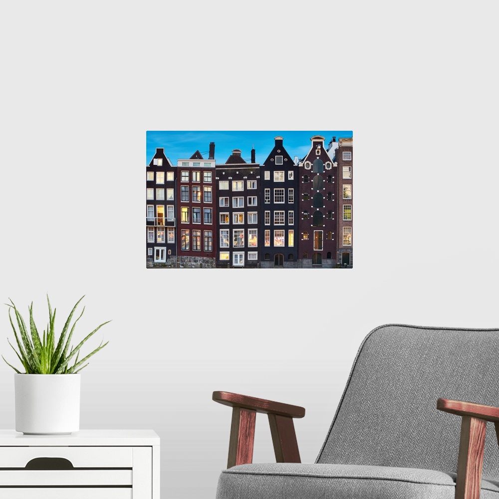 A modern room featuring Netherlands, North Holland, Amsterdam, Typical Dutch houses along the Damrak Canal.