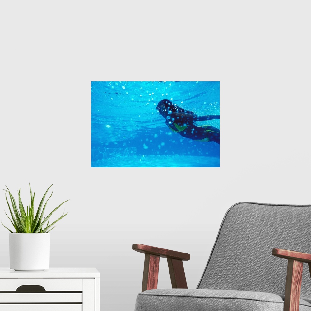 A modern room featuring Young woman swimming underwater, in pool
