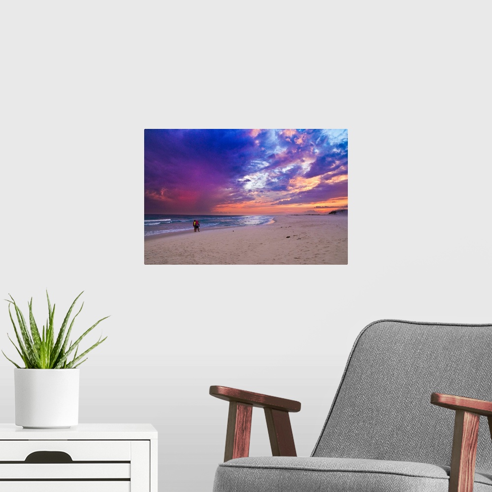A modern room featuring People walking on the beach during a pink and purple sunset along the Gulf Islands National Seash...
