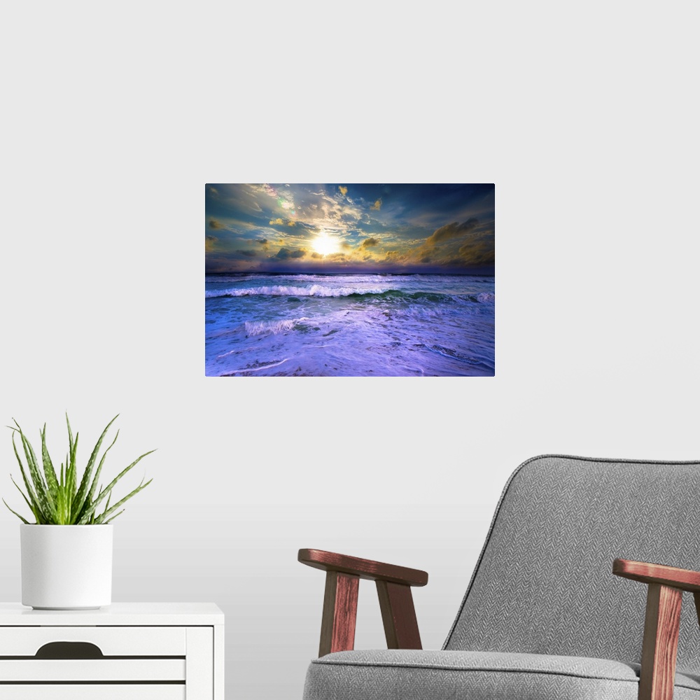 A modern room featuring A bright yellow sunset with blue waves crashing on the beach.
