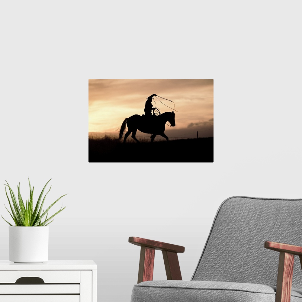 A modern room featuring A photograph of a silhouette of a cowboy riding a horse in a field with a sunset.