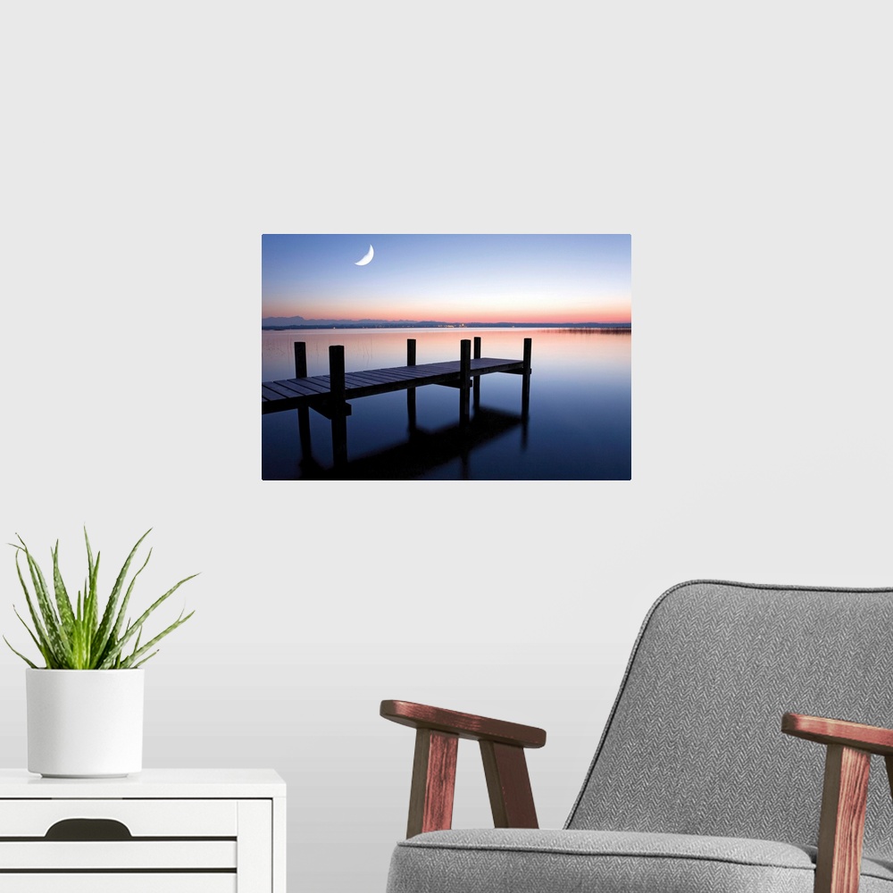 A modern room featuring Sunset photograph of a dock over calm water and a half moon in the sky.