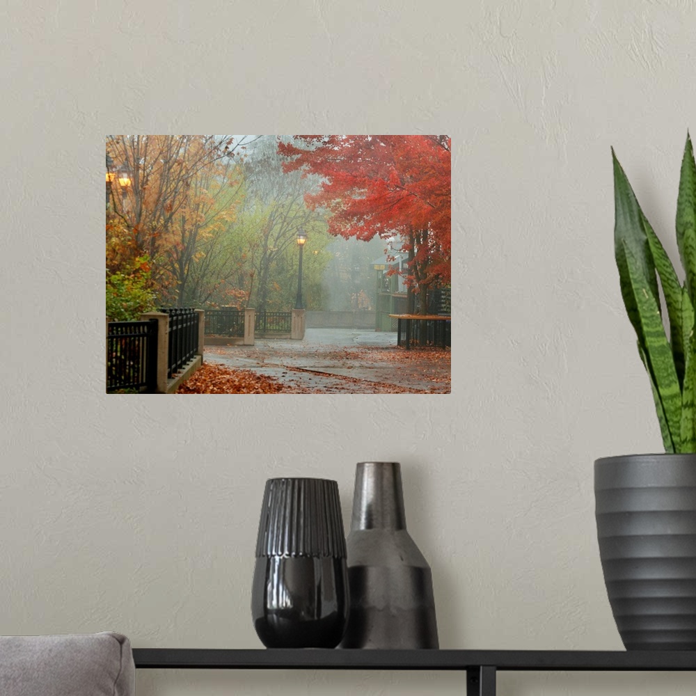 A modern room featuring A photograph of a city walkway covered with autumn leaves on a misty day.