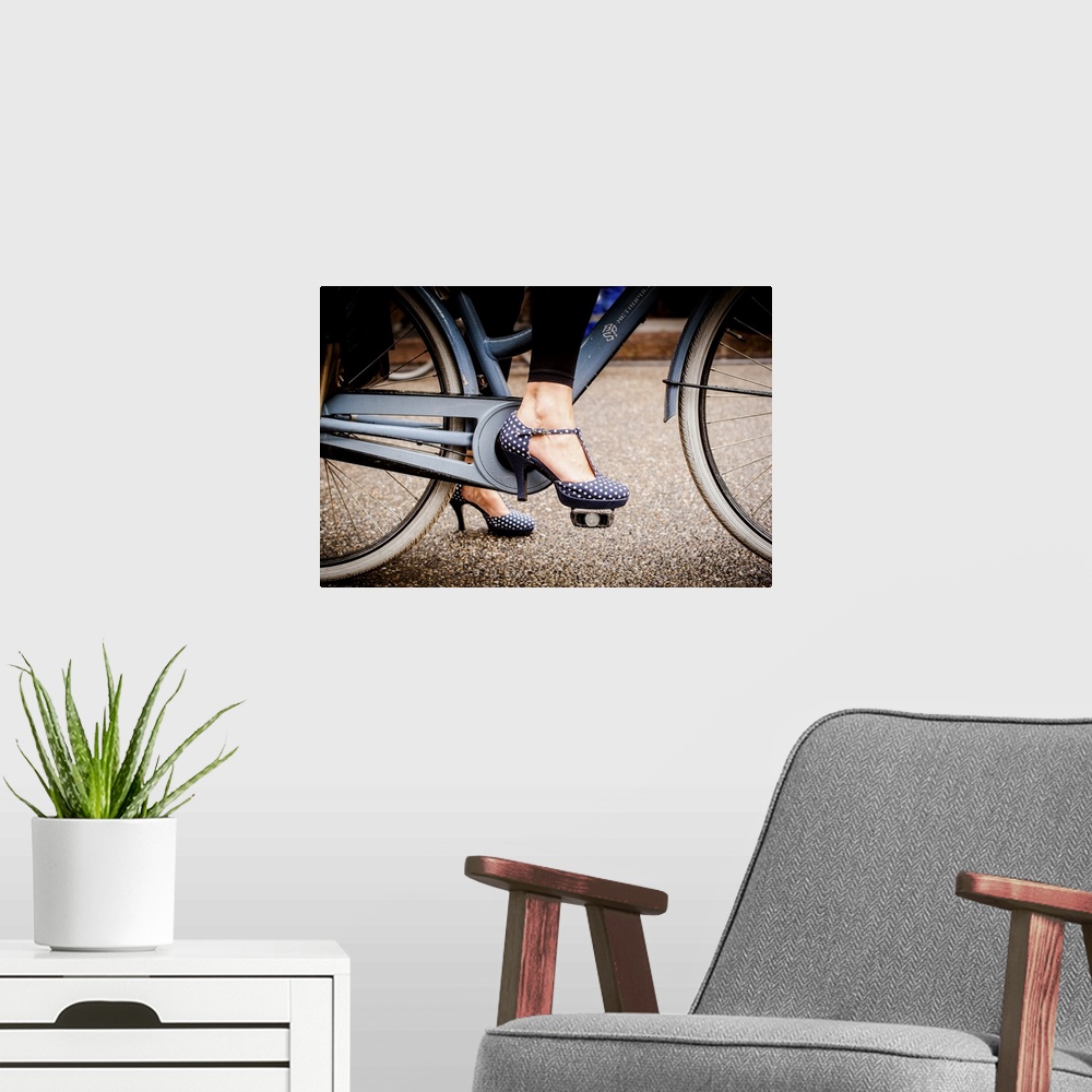 A modern room featuring A woman in dotted high heels stepping onto the a bike pedal.