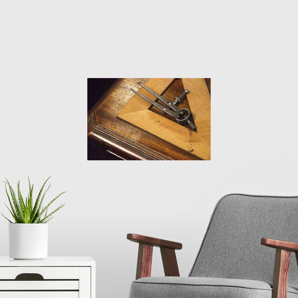 A modern room featuring Antique set square and pair of compasses on wooden table