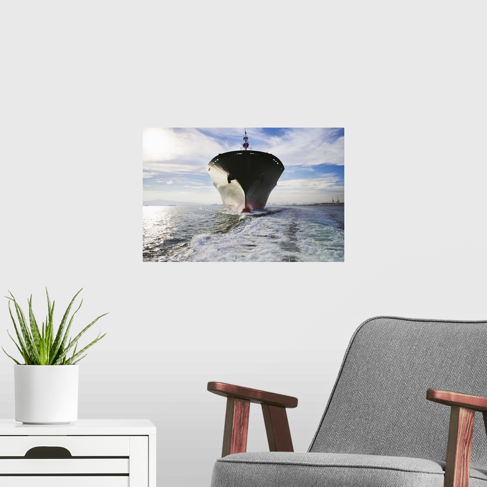 A modern room featuring Bow view of cargo ship sailing out of port.