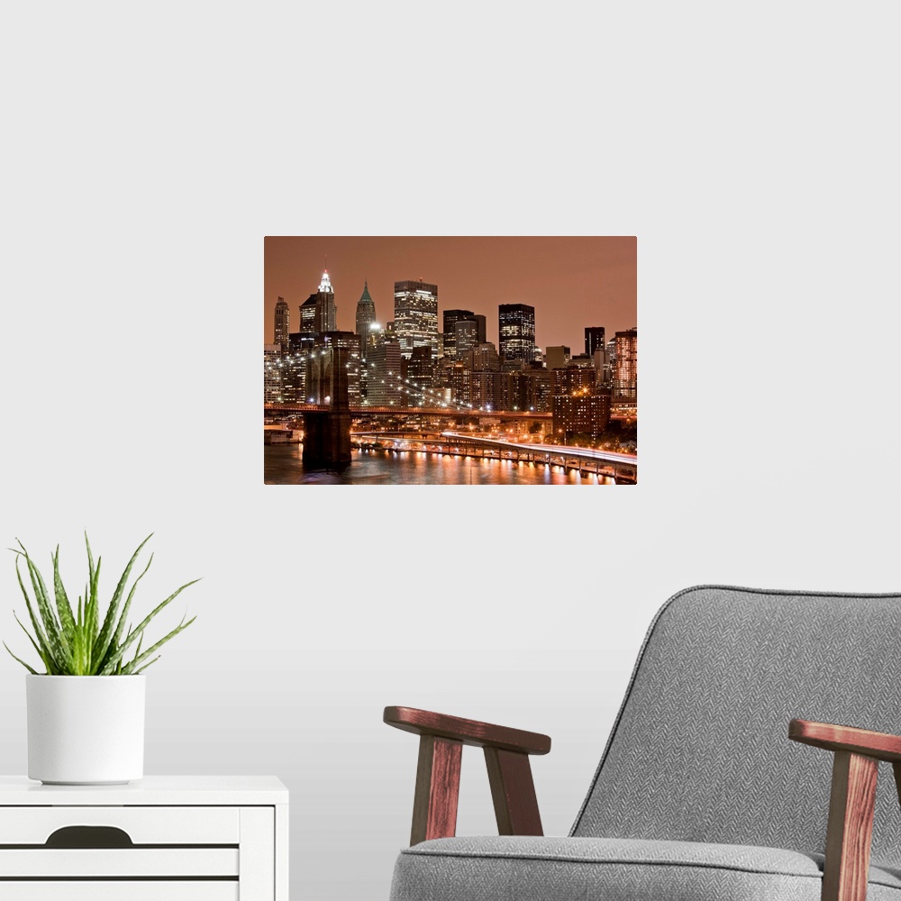 A modern room featuring USA, New York, Brooklyn, Brooklyn Bridge at night and East River with Lower Manhattan skyline glo...
