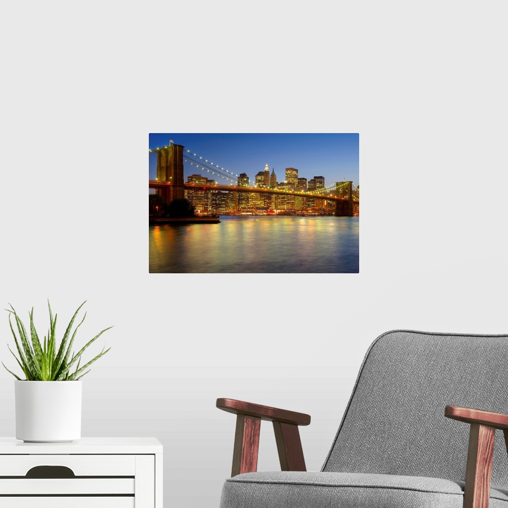 A modern room featuring Photograph of skyline and waterfront after sunset.  The buildings lights are reflected in the wat...