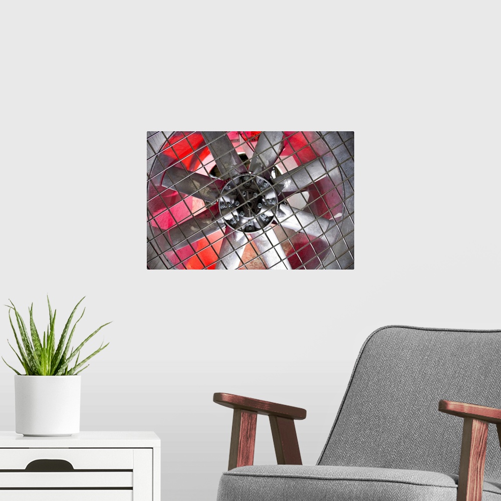 A modern room featuring Close-up of an industrial ventilation fan with red hues lighting up the back.