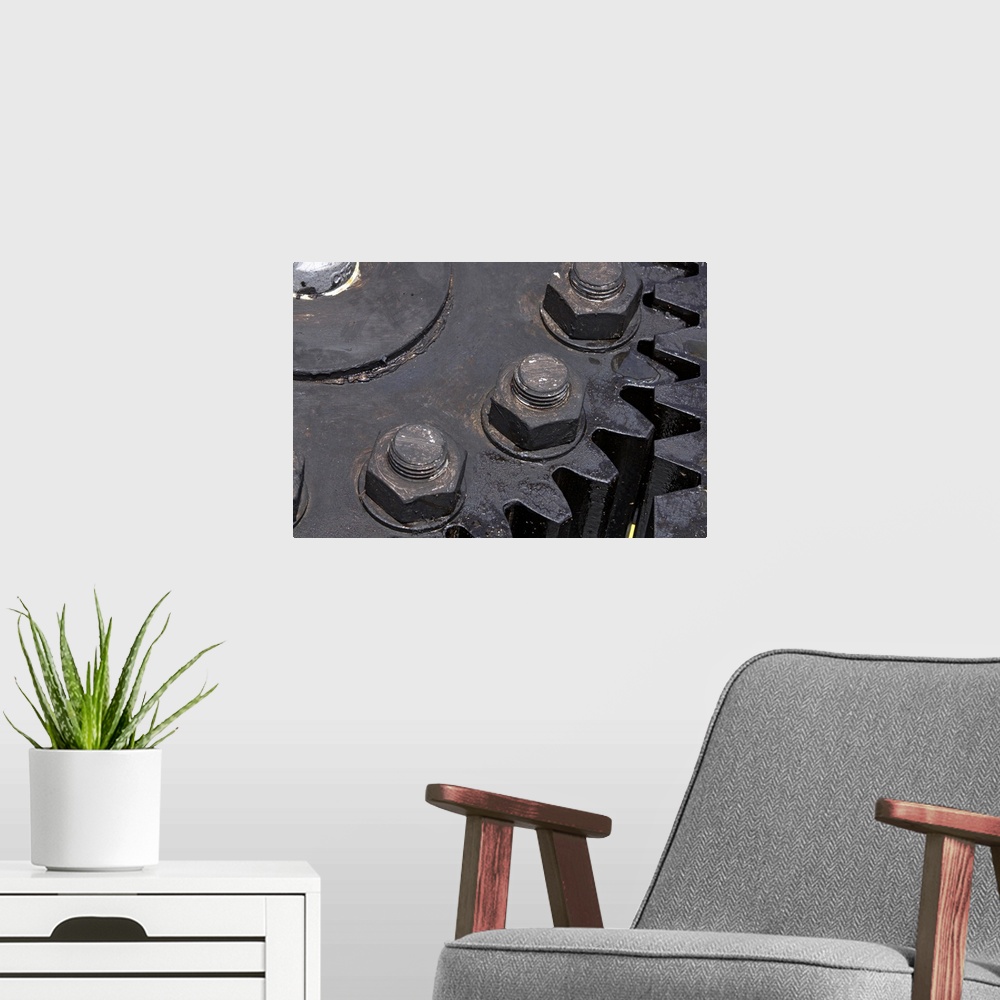 A modern room featuring Oversized, horizontal, close up photograph of the teeth meeting on two large metal gears. Large b...
