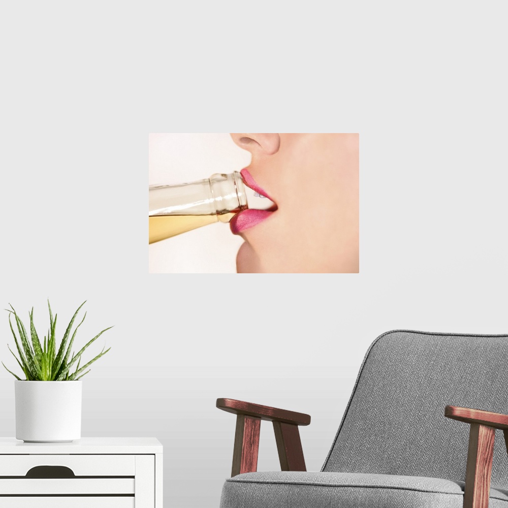 A modern room featuring This picture is taken closely of a woman's mouth as she begins to take a sip from a bottled drink.