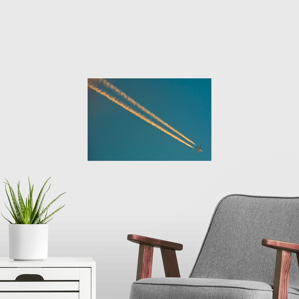 A modern room featuring Long condensation trails in blue sky at sunset.