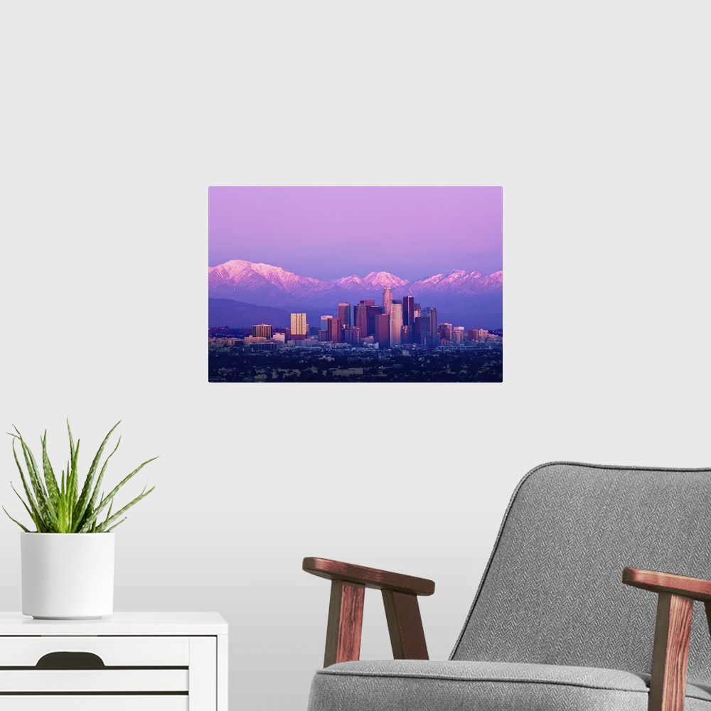 A modern room featuring Downtown Los Angeles and sunset. Buildings are lit from setting sun and mountains are capped with...