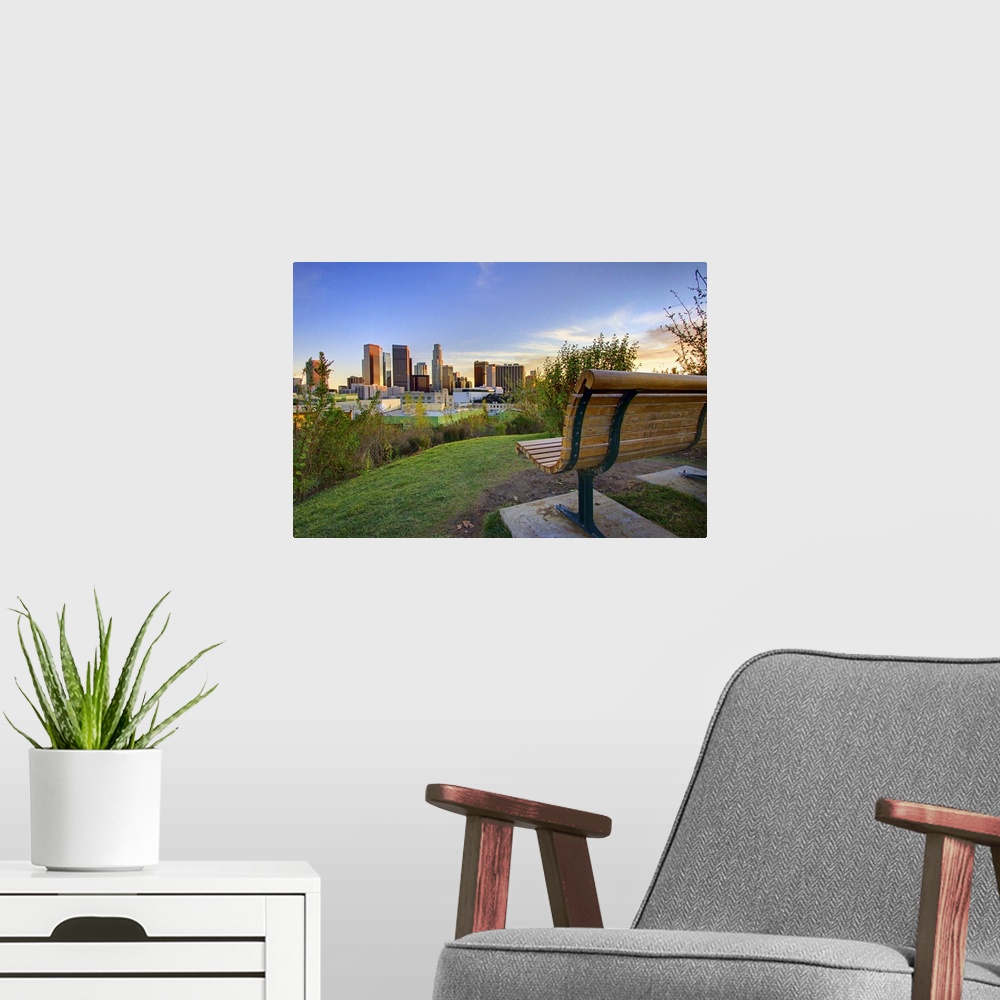 A modern room featuring Photograph of park bench overlooking city skyline at dusk.