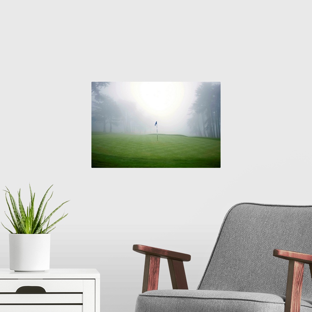 A modern room featuring Flag on putting green on golf course, fog and trees in background