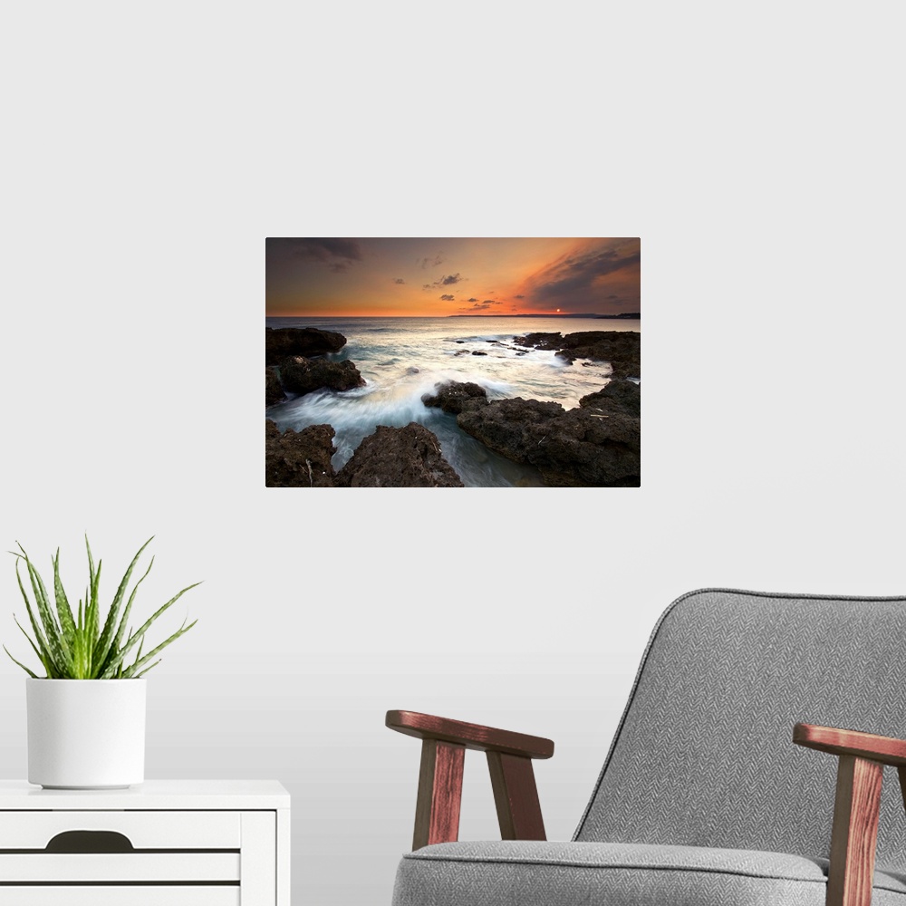 A modern room featuring Frog Rock, kenting at dusk with foaming waves rushing in and crashing on dark coral reefs while s...