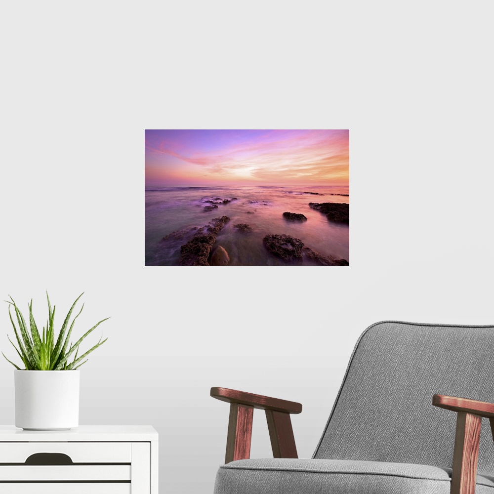 A modern room featuring Purple clouds spreading above Wanliton sky at dusk and sea water crashing on coral reefs; in Ping...