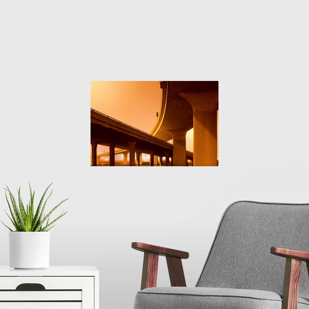 A modern room featuring Concrete supports of towering highway overpasses leading into downtown on a foggy spring night.