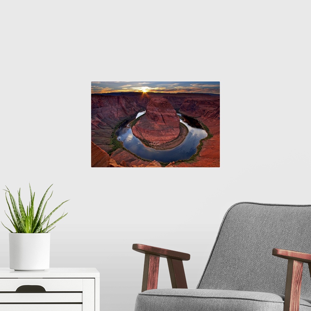 A modern room featuring Photograph of river circling huge rock formation at sunset under a cloudy sky.