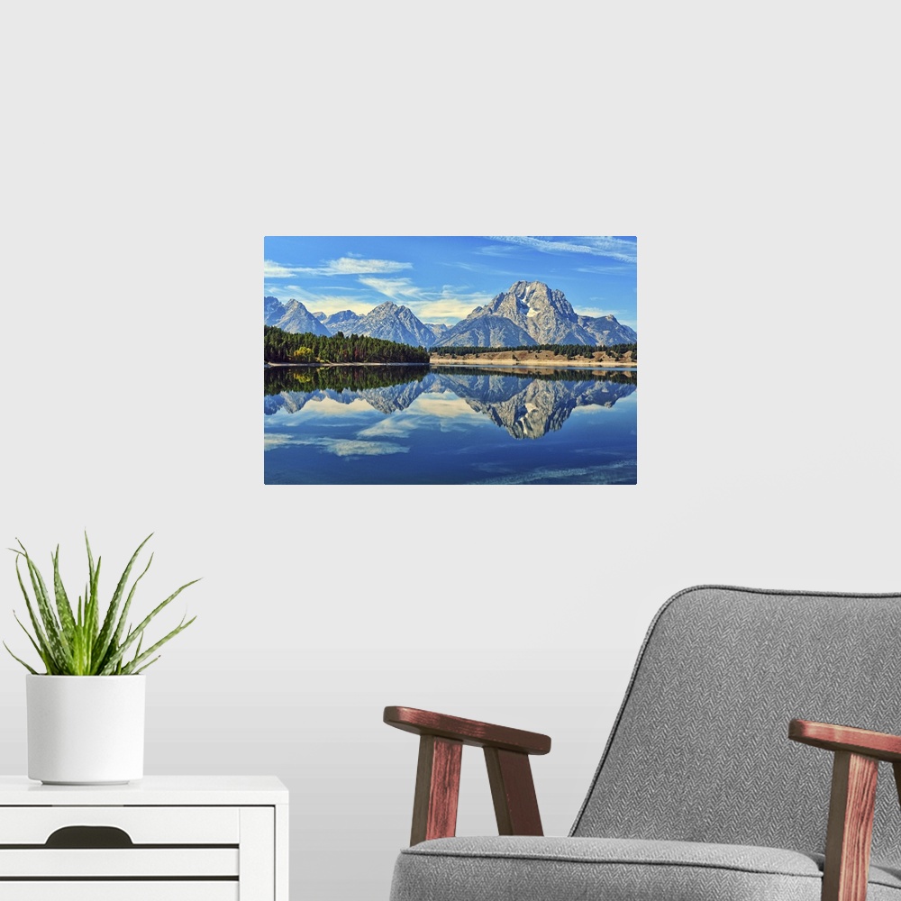 A modern room featuring A reflection of Mount Moran and the Teton mountain range in the still waters of Jackson Lake in G...