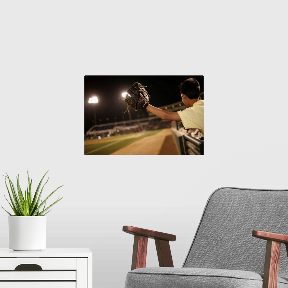 A modern room featuring Kid leaning over wall to try and catch 'foul 'ball  (hit out of play)at nighttime baseball game