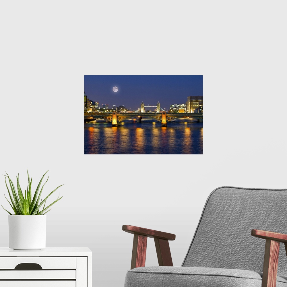A modern room featuring Horizontal photograph on a giant wall hanging of the Millennium Footbridge, lit at night over the...