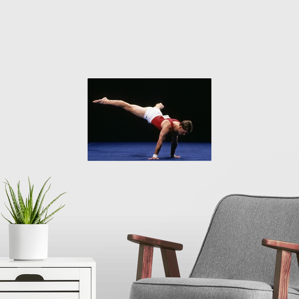 A modern room featuring Male gymnast peforming a routine in the floor exercise