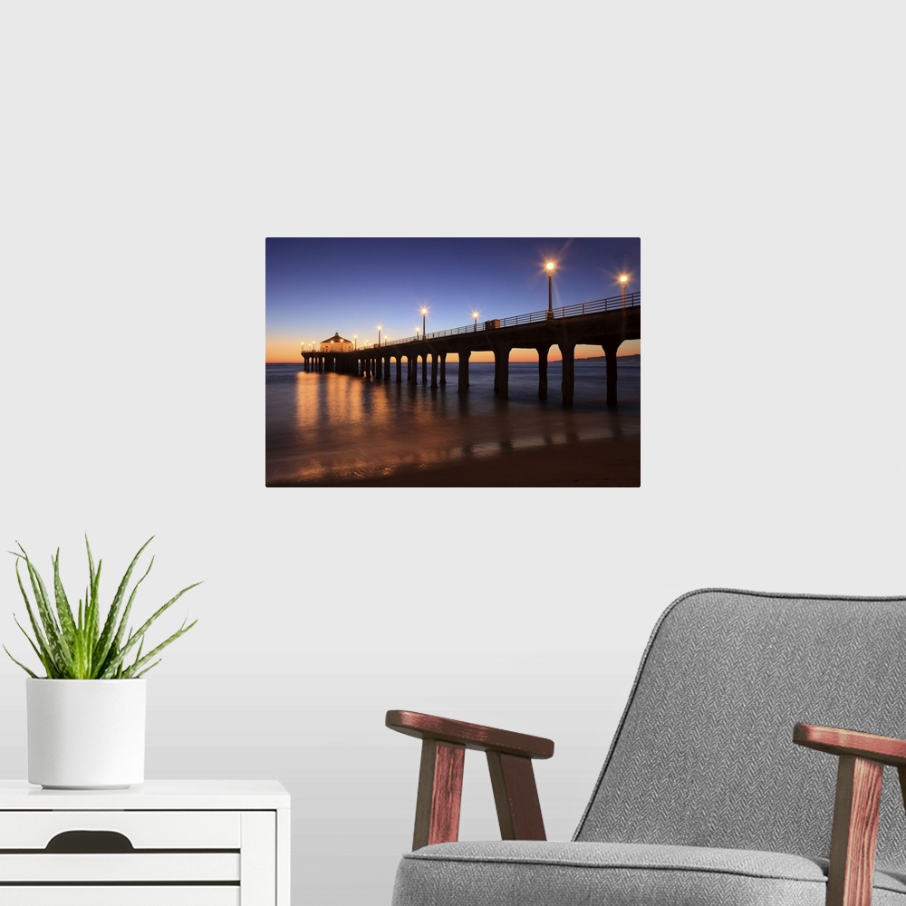 A modern room featuring Big canvas print of a pier that is silhouetted against a sunset with lights lit up along it.