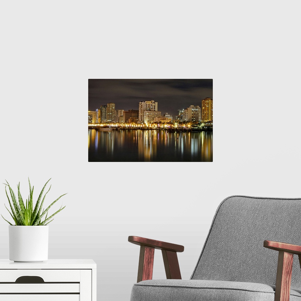 A modern room featuring Wall docor of a city in the Philippines illuminated at night reflected on the water.