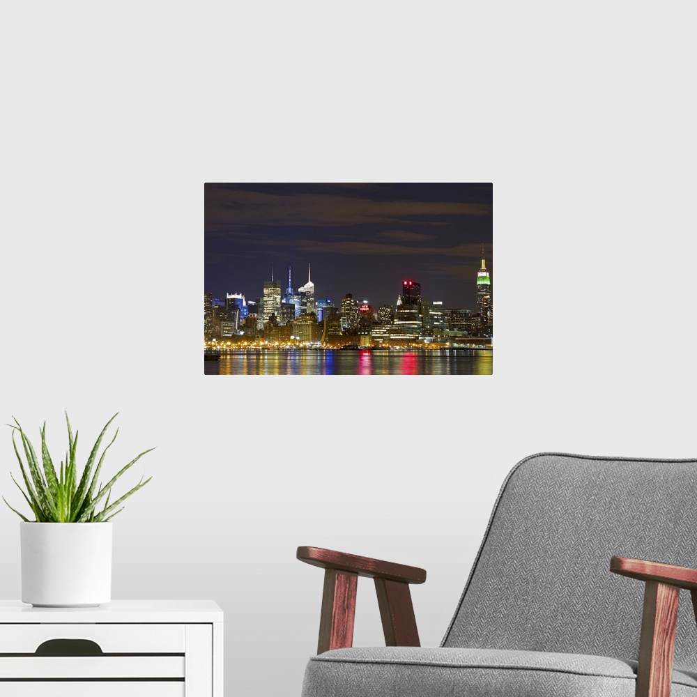 A modern room featuring Giant landscape photograph of the brightly lit Manhattan skyline at night, reflecting in the water.