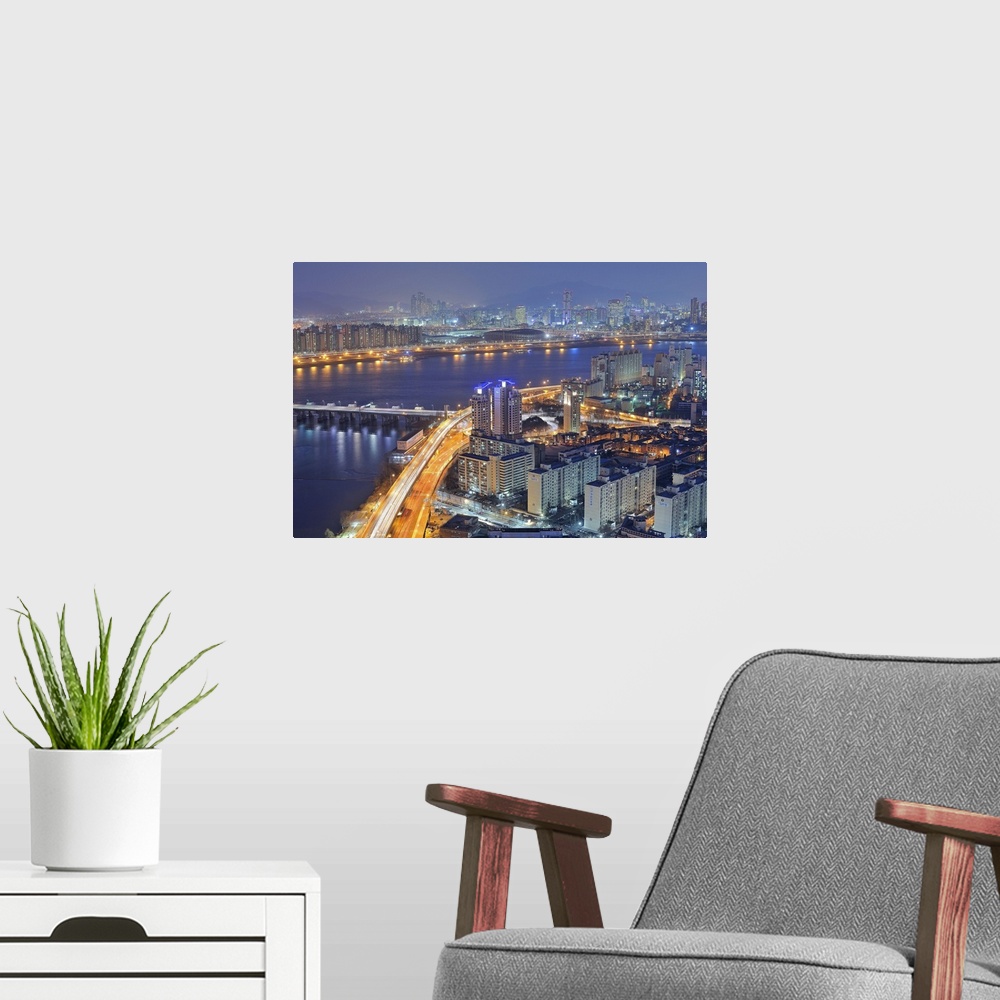 A modern room featuring Big canvas photo of a city in Korea lit up at night along the water.