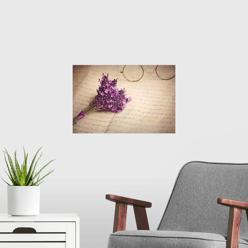 A modern room featuring Old handwritten letter, pair of old fashioned round horn rimmed glasses and posy of lavender.