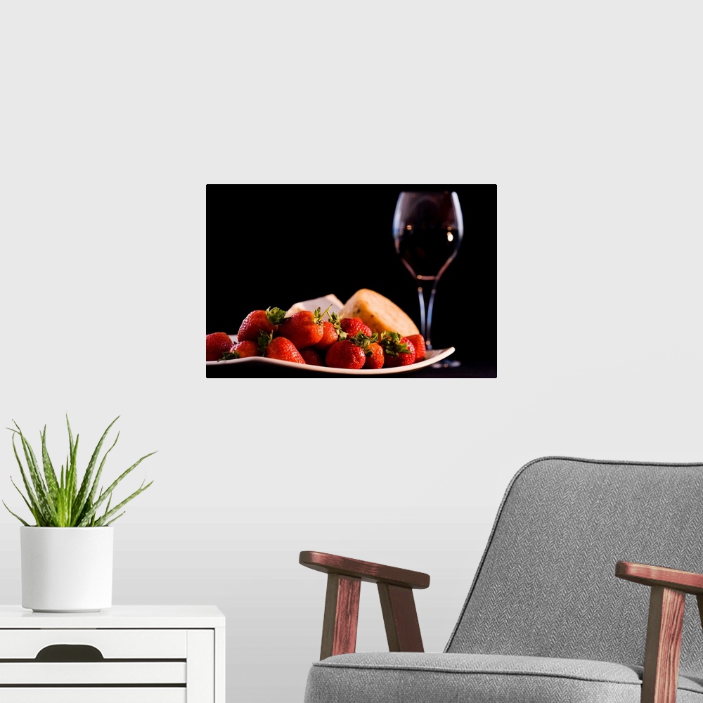 A modern room featuring This is a horizontal photograph of fruit, cheeses, and wine against a dark backdrop making this a...