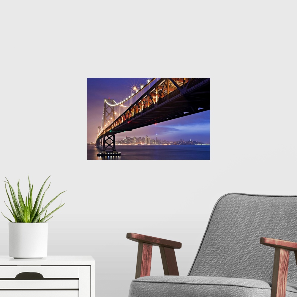 A modern room featuring This oversized piece is a photograph taken from below the bridge that is fully lit during the nig...