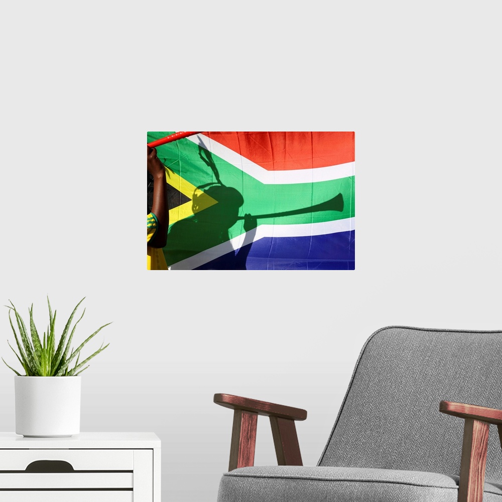 A modern room featuring Shadow of soccer supporter blowing vuvuzela, South African flag in background, Johannesburg, Sout...