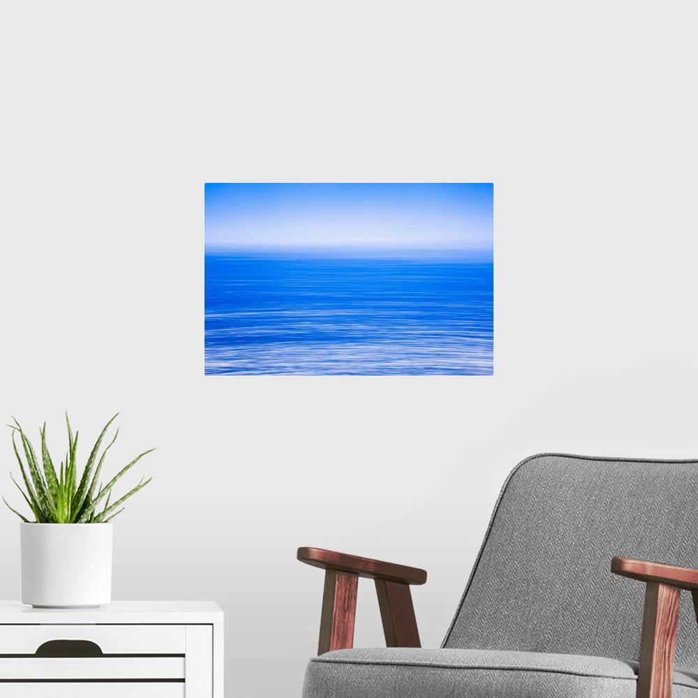 A modern room featuring Silky calm blue open sea [ocean] with fog or mist over water. Blue sky.