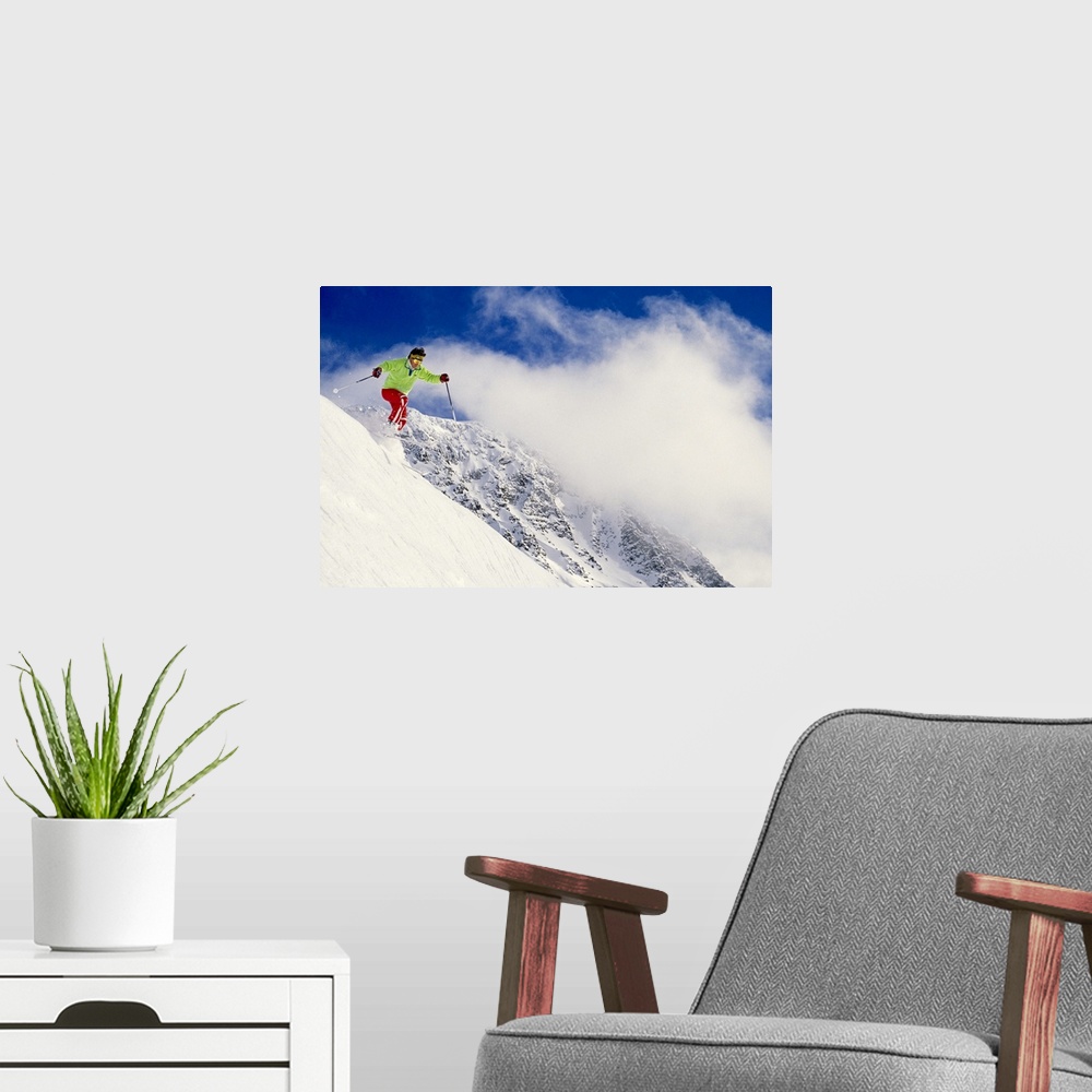 A modern room featuring Photograph of man on skis coming down snowy slope with huge mountain in background under a cloudy...