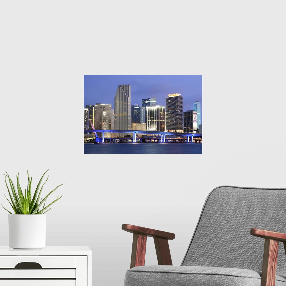 A modern room featuring Large canvas photo art of the Miami cityscape lit up at night along the waterfront.