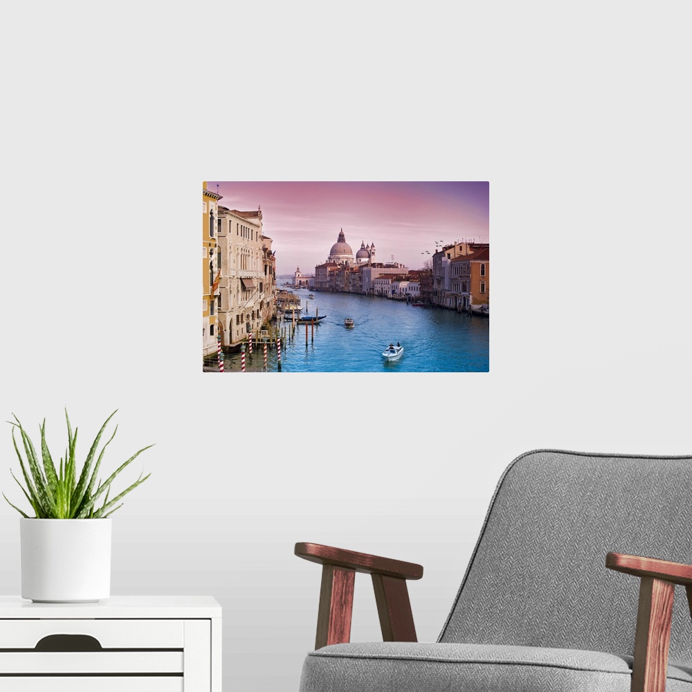 A modern room featuring Wall art of buildings on either side of an Italian canal with boats floating through the water.