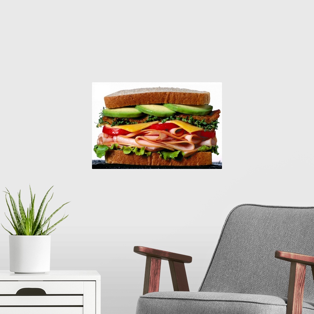 A modern room featuring Stacked turkey sandwich with avocados, cheese, tomatoes and crunchy lettuce
