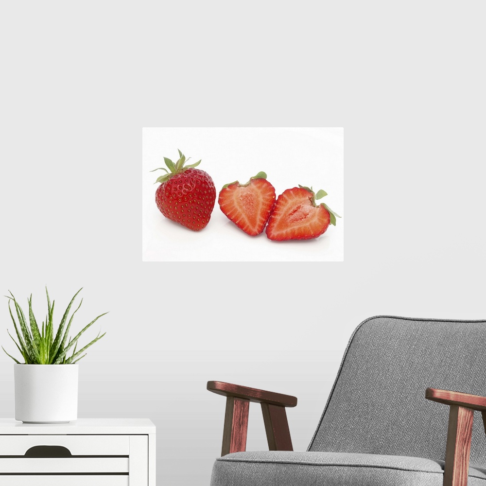 A modern room featuring Two fresh, ripe, home grown, organic strawberries, one cut into two halves, on a white background.