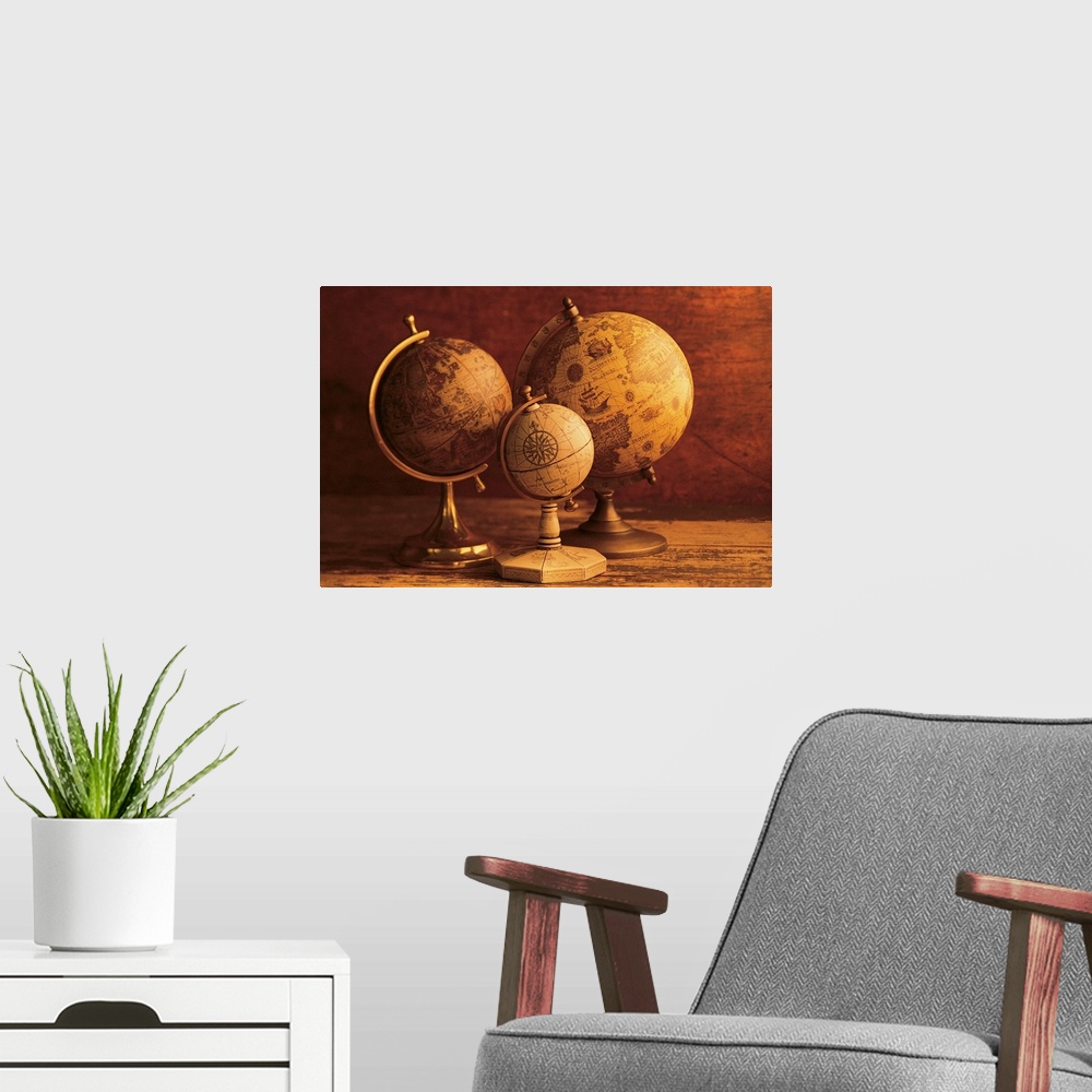 A modern room featuring Photograph of three vintage globes of varying sizes sitting on a map table.
